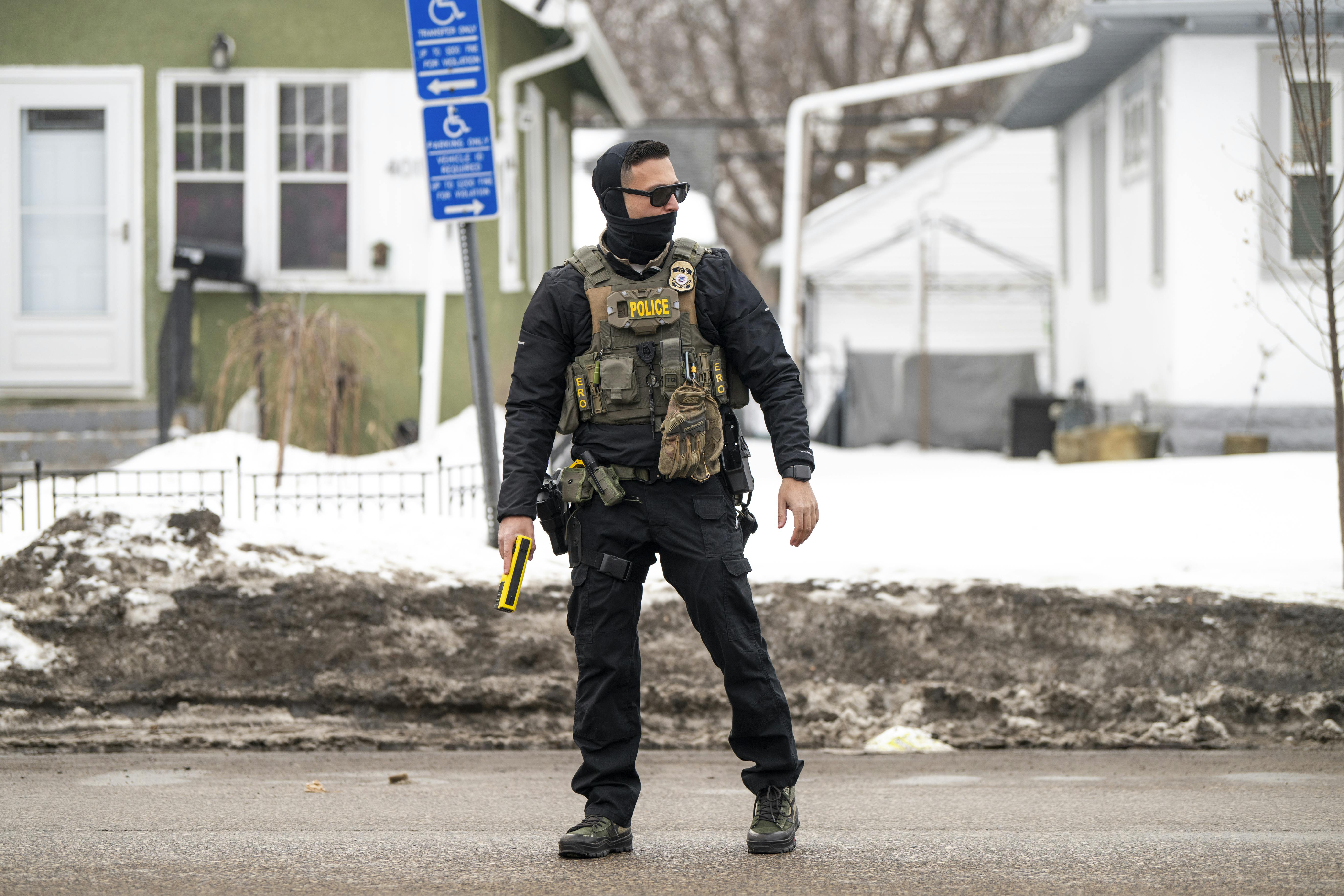 An ICE agent holds a taser as they stand watch after one of their vehicles got a flat tire on Penn Avenue on February 5, 2026 in Minneapolis, Minnesota.