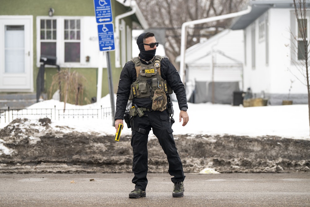 An ICE agent holds a taser as they stand watch after one of their vehicles got a flat tire on Penn Avenue on February 5, 2026 in Minneapolis, Minnesota.