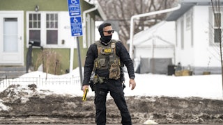 An ICE agent holds a taser as they stand watch after one of their vehicles got a flat tire on Penn Avenue on February 5, 2026 in Minneapolis, Minnesota.