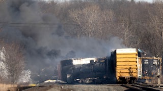 Cargo train lays off the tracks, as smoke rises