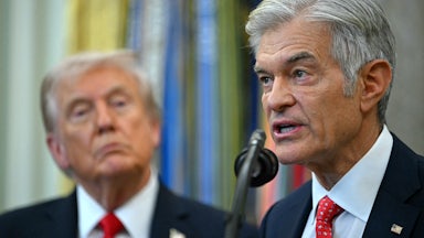 Dr. Oz speaks into a microphone in the Oval Office while Donald Trump stands behind him and watches