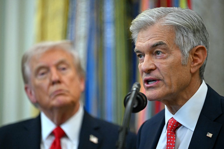 Dr. Oz speaks into a microphone in the Oval Office while Donald Trump stands behind him and watches