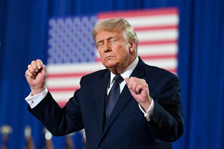 Donald Trump holds up clenched fists with eyes closed