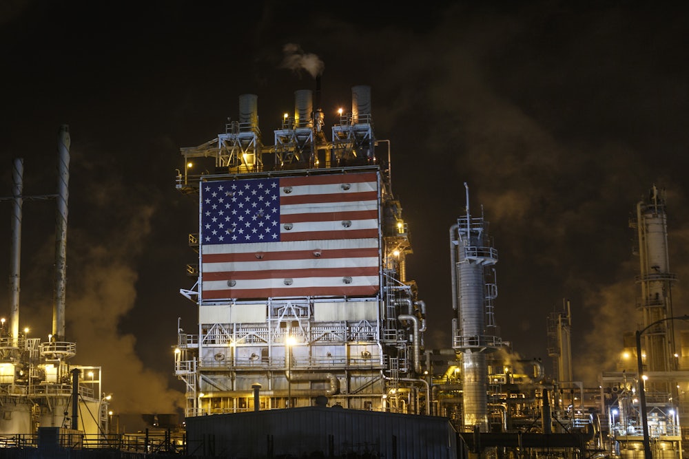 An American flag is displayed among smokestacks and lights.
