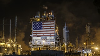 An American flag is displayed among smokestacks and lights.