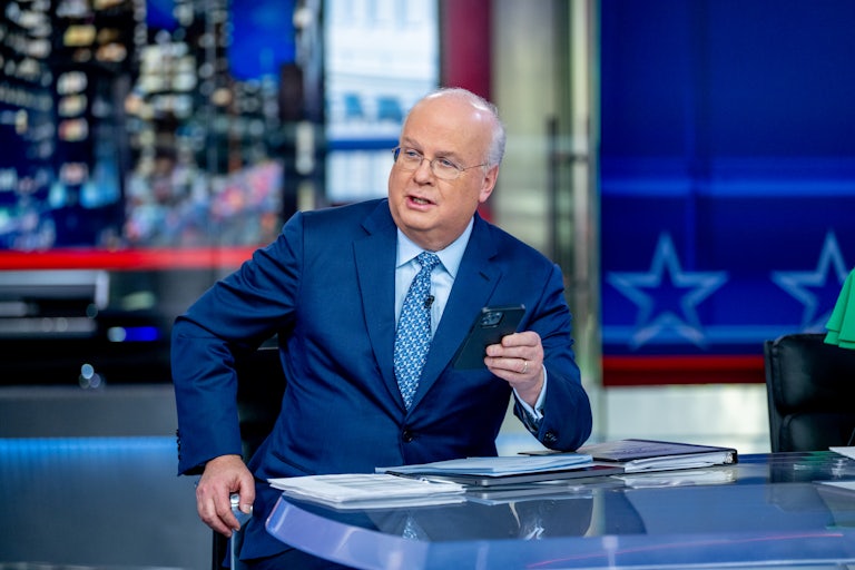 Karl Rove sits at a desk with his phone in his hand