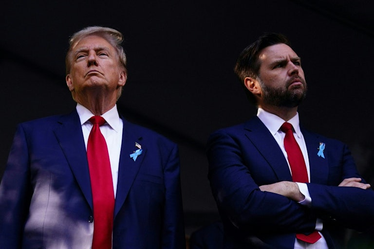 Donald Trump and JD Vance standing side by side, neither looking at each other. Vance croses his arms and turns his head away.