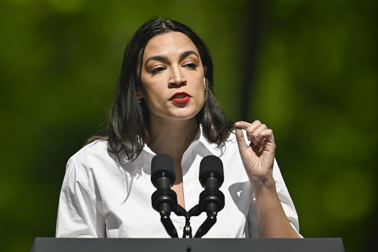 Alexandria Ocasio-Cortez gestures as she speaks into microphones