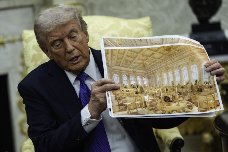Donald Trump holds up a photo simulation of the White House ballroom while sitting in the Oval Office.