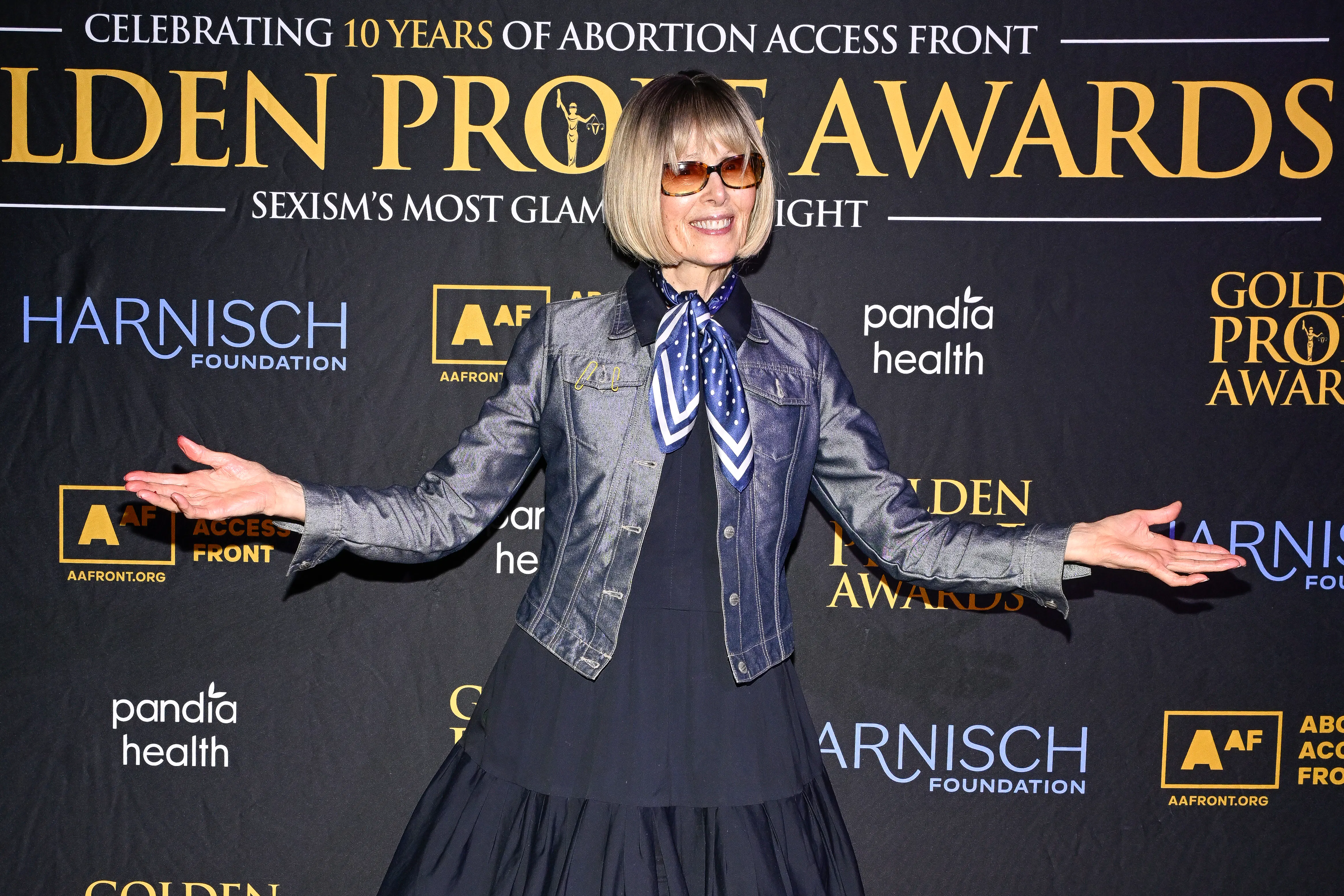 E. Jean Carroll holds her arms out to the side while posing on the red carpet at an event