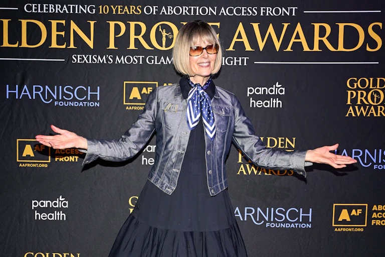 E. Jean Carroll holds her arms out to the side while posing on the red carpet at an event