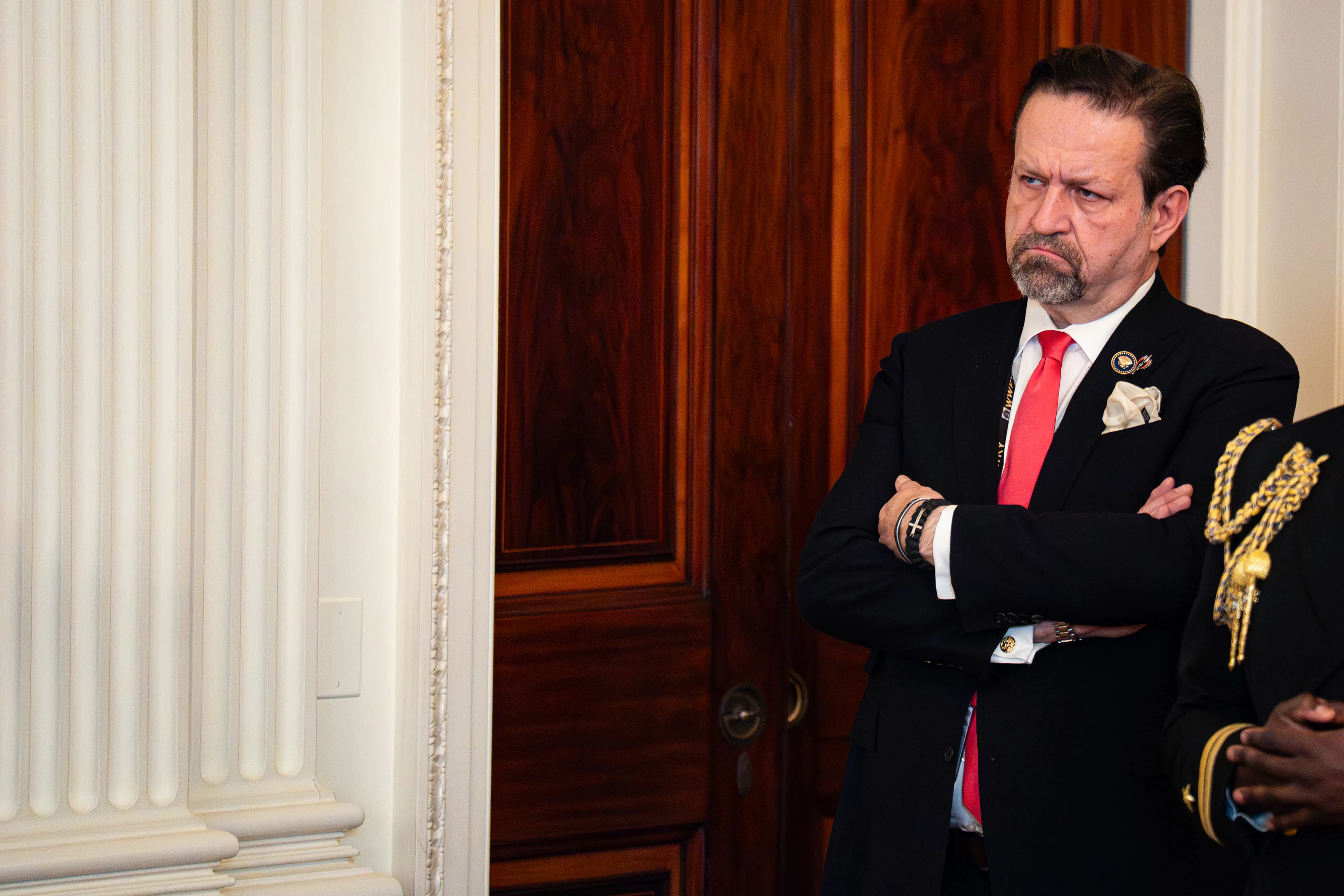 Sebastian Gorka frowns and stands with his arms crossed during an event at the White House