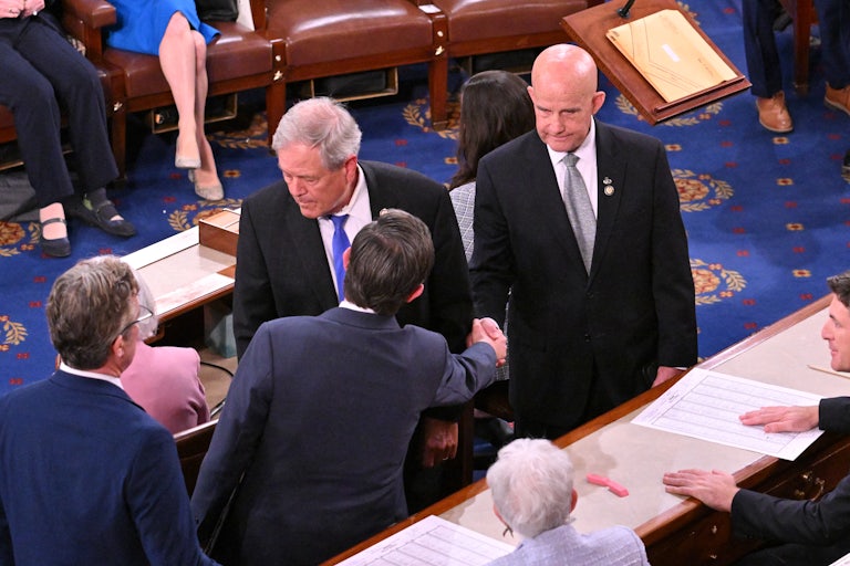 Keith Self and Mike Johnson shake hands surrounded by colleagues.