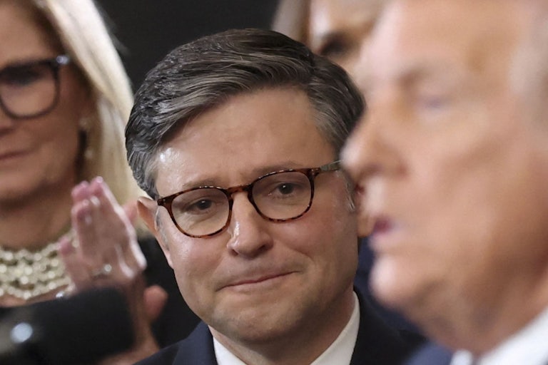 Mike Johnson watches Donald Trump speak