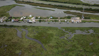 An aerial shot of homes on Ridgeway Boulevard in New Orleans, near Lake Pontchartrain, surrounded by water and marshland.