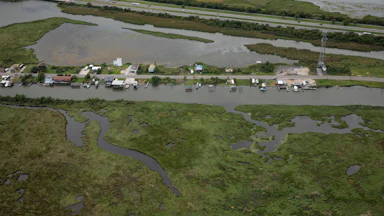 An aerial shot of homes on Ridgeway Boulevard in New Orleans, near Lake Pontchartrain, surrounded by water and marshland.