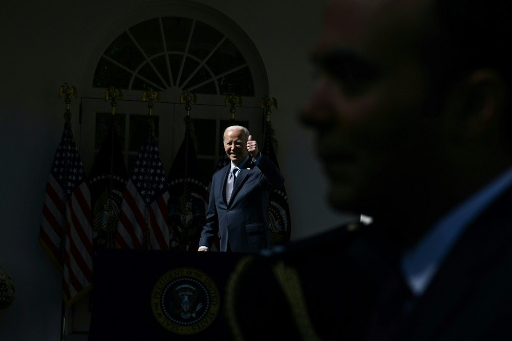 Joseph Biden gives a thumbs up in the darkness as a man blocks a camera.