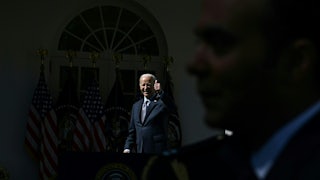 Joseph Biden gives a thumbs up in the darkness as a man blocks a camera.