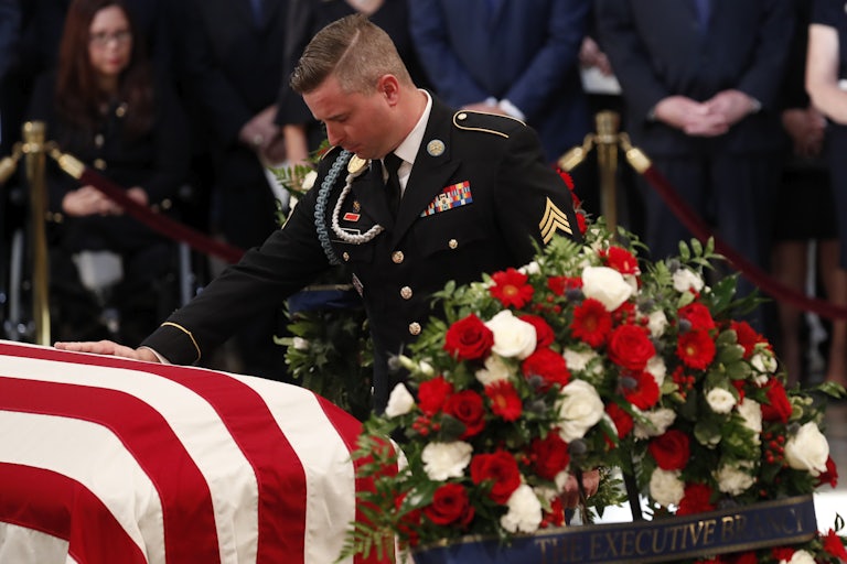 Jimmy McCain bows his head and touches his father's casket, draped in a U.S. flag.