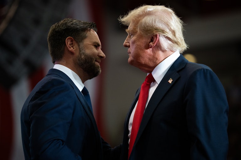 J.D. Vance and Donald Trump stand facing each other on stage at a rally
