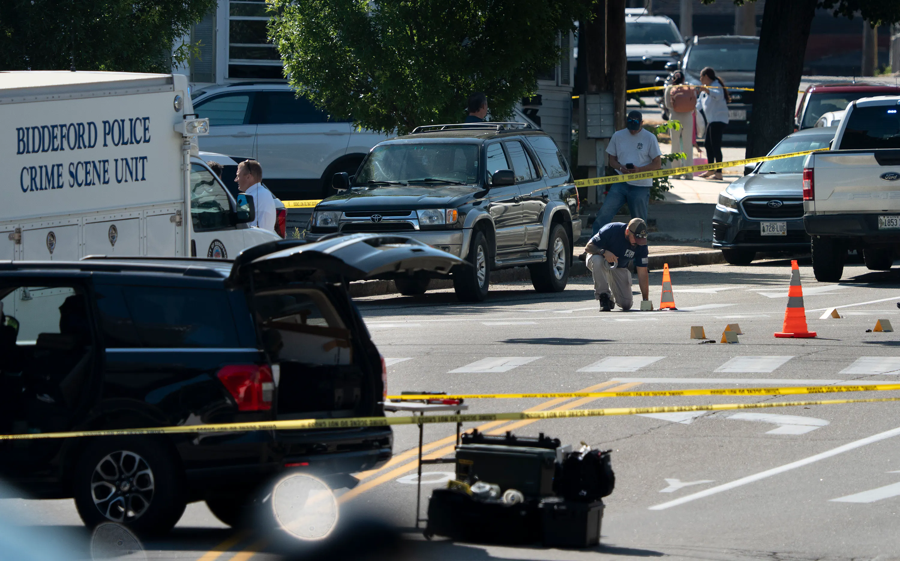 An FBI official places an evidence card on Pool Street in Biddeford where a man was fatally shot by ICE agents, July 13.