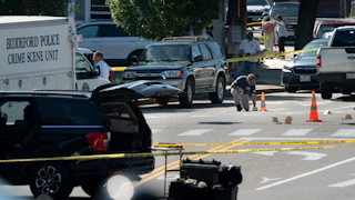 An FBI official places an evidence card on Pool Street in Biddeford where a man was fatally shot by ICE agents, July 13.