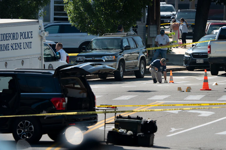 An FBI official places an evidence card on Pool Street in Biddeford, Maine, where a man was fatally shot by ICE agents on July 13.