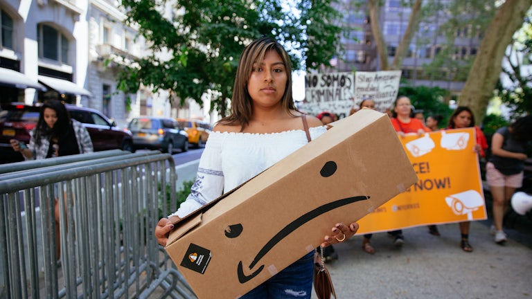 A protester holds an Amazon box while demonstrating against Jeff Bezos.