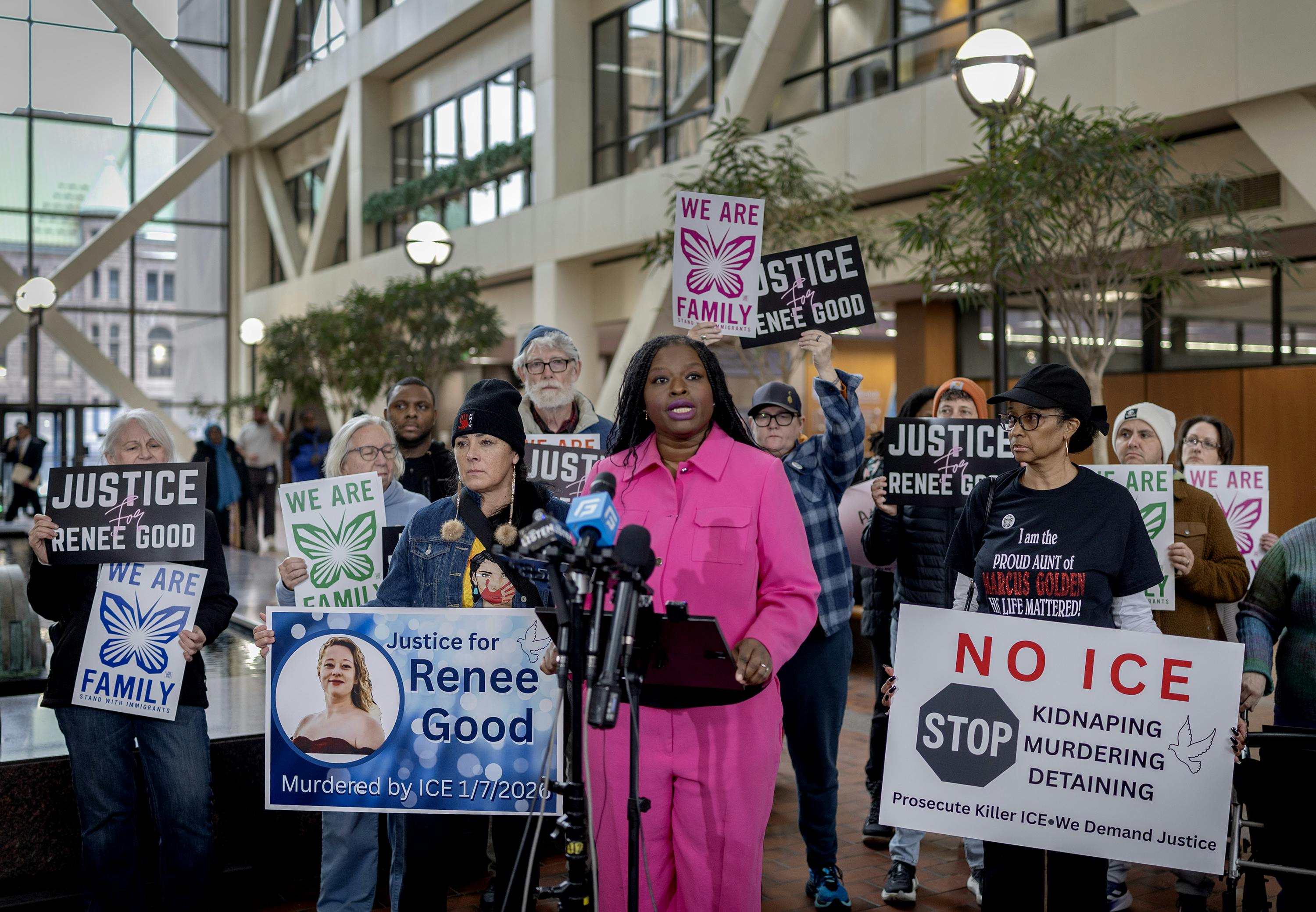 Nekima Levy Armstrong speaksk during a press conference as others hold signs against ICE and in remembrance of Renee Good.